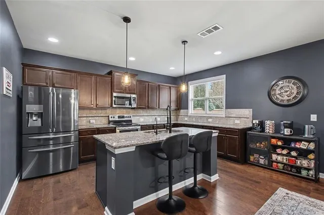 a kitchen with kitchen island granite countertop wooden cabinets a counter top space appliances and a center island