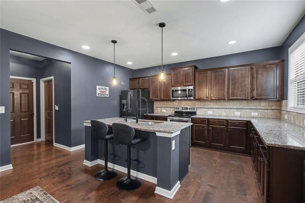 3499 In Bloom Way Auburn, GA 30011 - Photo 12 of 30 a kitchen with kitchen island granite countertop wooden cabinets a counter top space appliances and a center island