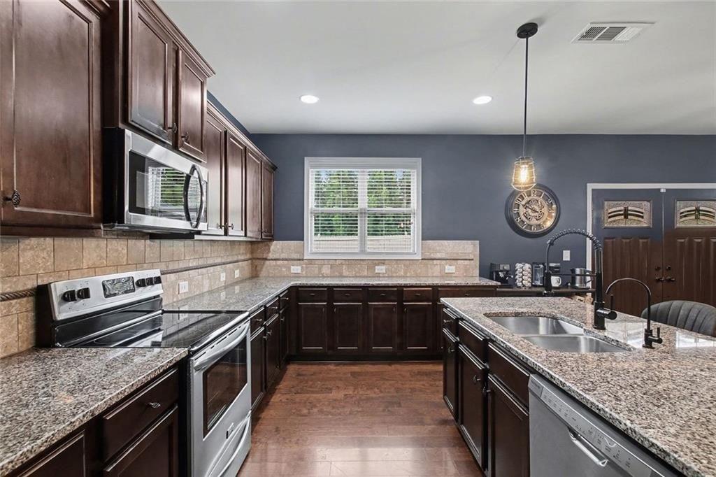 3499 In Bloom Way Auburn, GA 30011 - Photo 13 of 30 a kitchen with stainless steel appliances granite countertop a sink stove and refrigerator