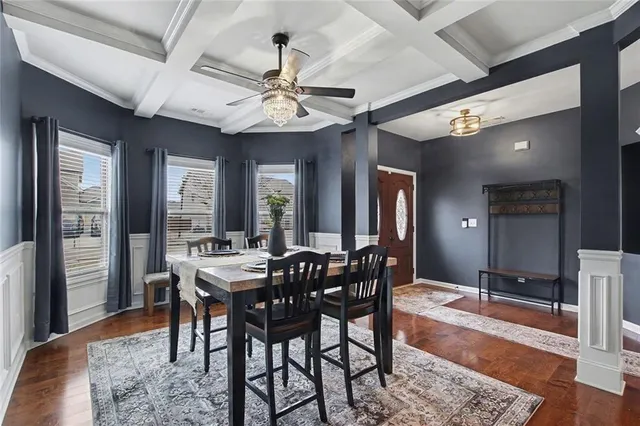 a kitchen with stainless steel appliances kitchen island granite countertop a refrigerator oven a sink a dining table and chairs with wooden floor