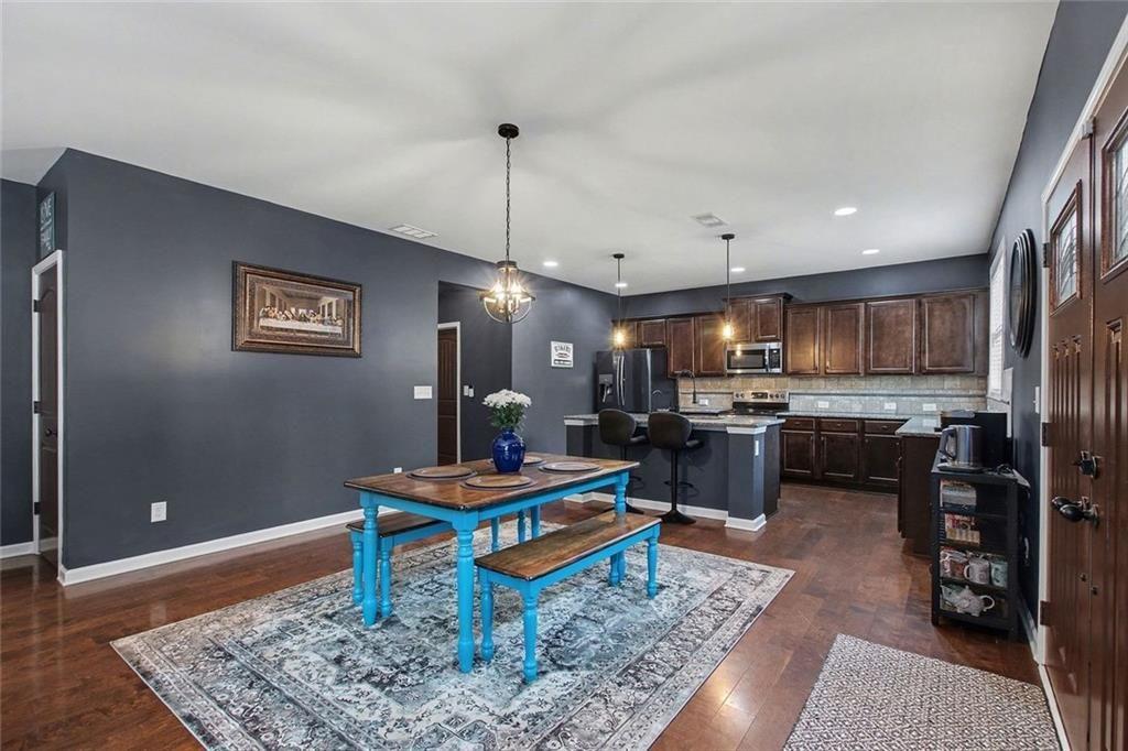 3499 In Bloom Way Auburn, GA 30011 - Photo 10 of 30 a kitchen with stainless steel appliances kitchen island granite countertop a refrigerator dining table and chairs