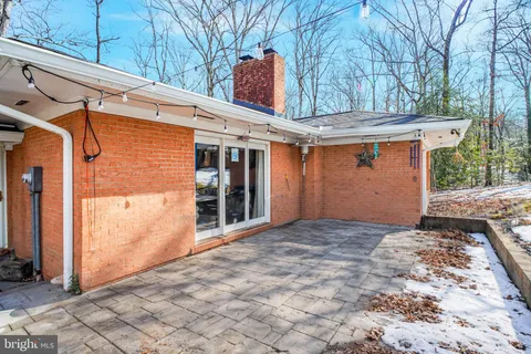 a backyard of a house with large trees and outdoor seating