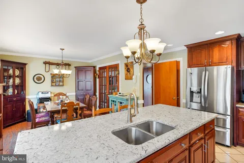 a kitchen with stainless steel appliances granite countertop a sink dishwasher and couches with wooden floor