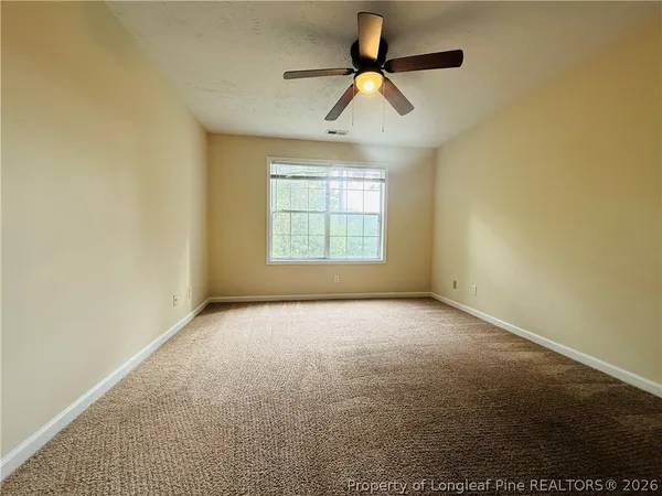 an empty room with ceiling fan and window