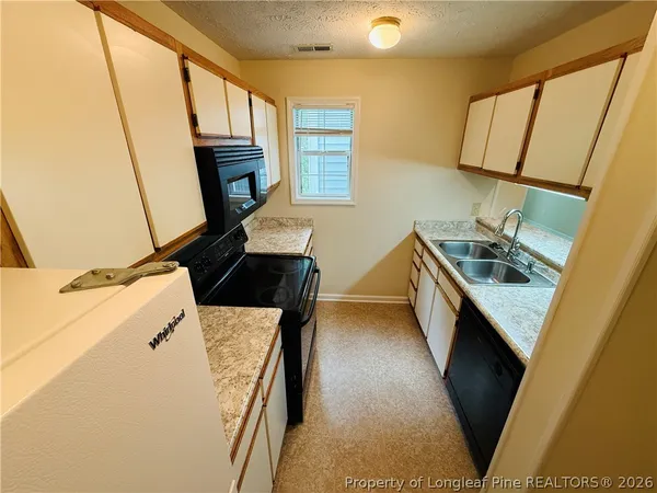 a kitchen with granite countertop a sink stove and refrigerator