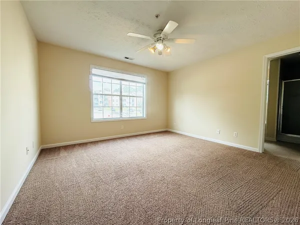 an empty room with windows and chandelier fan