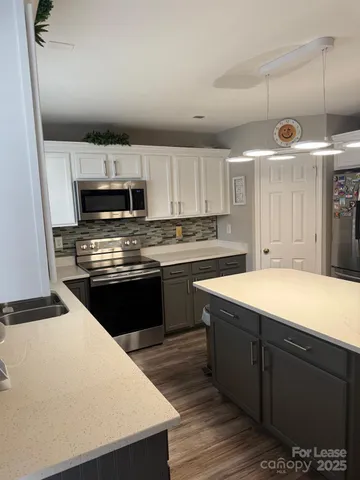 a kitchen with kitchen island a wooden floor and white appliances