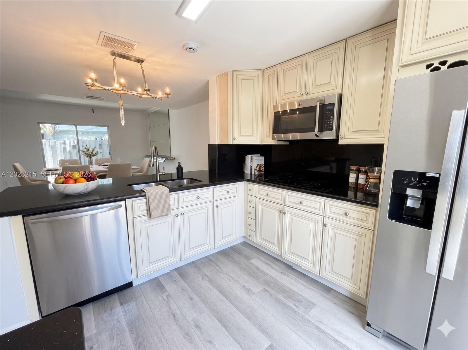 13 Southwest 3rd Street, Unit 13 Pompano Beach, FL 33060 - Photo 4 of 44 a kitchen with stainless steel appliances granite countertop a sink dishwasher a refrigerator and white cabinets with wooden floor