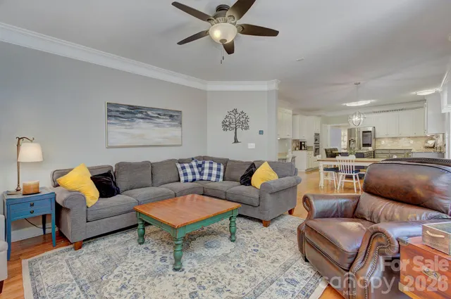 a living room with furniture kitchen view and a chandelier
