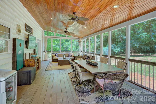a view of a patio with table and chairs potted plants with wooden floor and floor to ceiling window