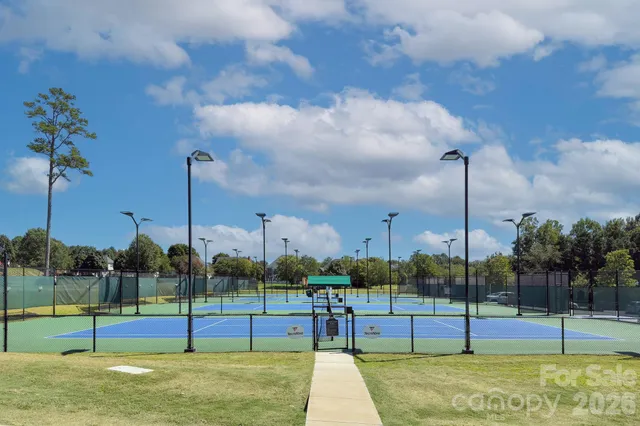 a view of a tennis ground with large trees