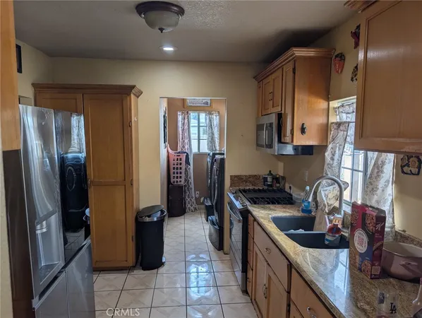 a kitchen with stainless steel appliances granite countertop a refrigerator a stove and a sink with wooden floor