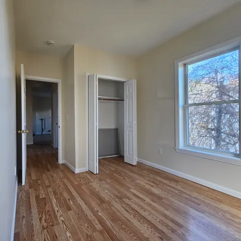 an empty room with wooden floor closet and windows
