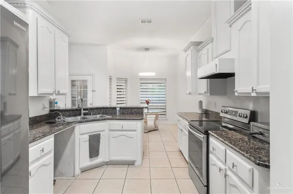 a kitchen with stainless steel appliances granite countertop a stove a sink and white cabinets