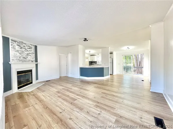 a view of empty room with wooden floor and fireplace