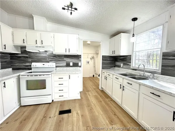 a kitchen with stainless steel appliances white cabinets a sink a stove a refrigerator and white cabinets