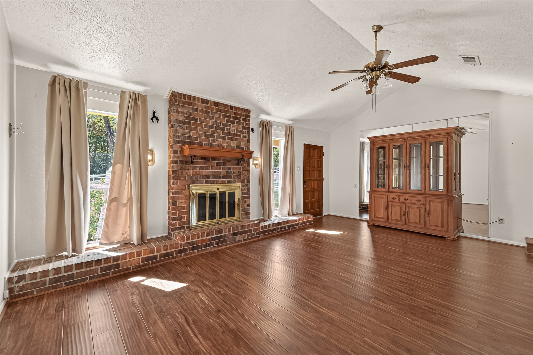 11535 Willis Waukegan Road Conroe, TX 77303 - Photo 12 of 47 This family room features a high ceiling with a ceiling fan, a warm brick fireplace, and large windows that let in natural light. The room has natural pecan laminate flooring with quite walk pad.