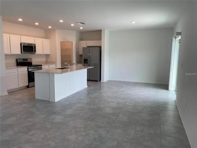 a large kitchen with stainless steel appliances a large counter top and a stove