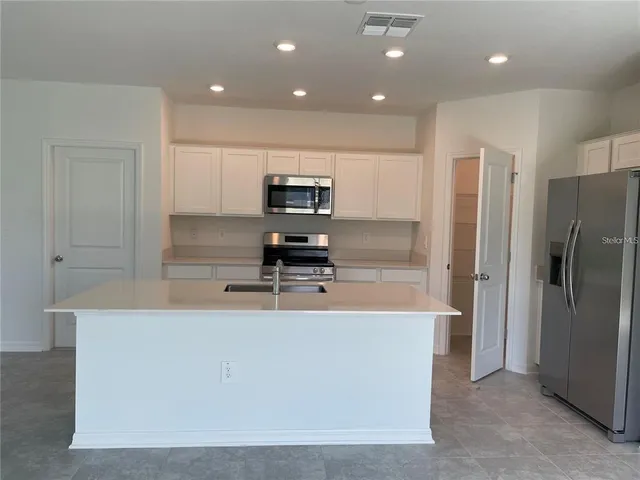 a large kitchen with stainless steel appliances a refrigerator and a stove top oven