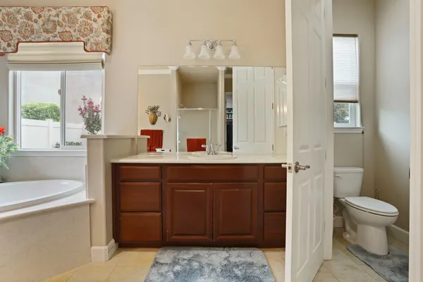a view of an empty room with kitchen and window