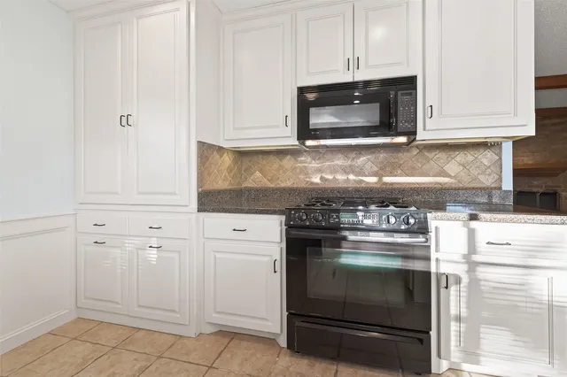 a kitchen with granite countertop white cabinets and stainless steel appliances