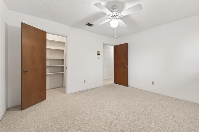 an empty room with closet and fan