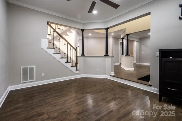 an empty room with wooden floor chandelier and windows