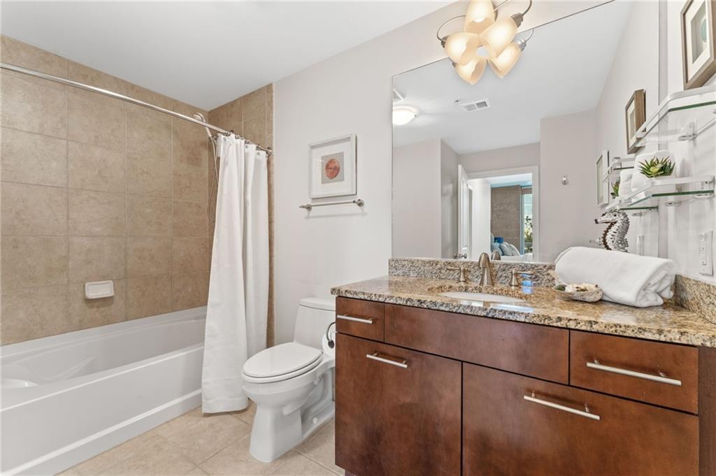 3300 Windy Ridge Parkway Southeast, Unit 809 Atlanta, GA 30339 - Photo 14 of 30 a bathroom with a granite countertop sink toilet a mirror and shower