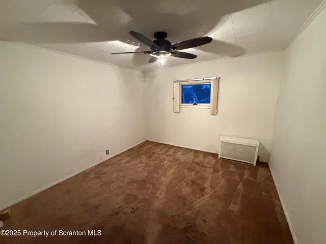 an empty room with a ceiling fan and window