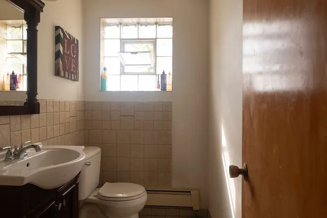 a bathroom with a toilet a sink a mirror a window and vanity