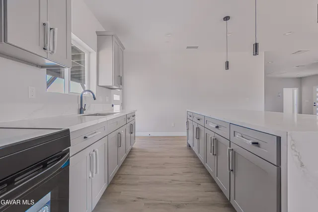 a kitchen with granite countertop lots of white cabinets and wooden floor