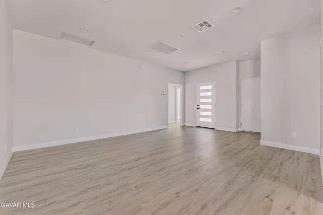 a view of empty room with wooden floor and window