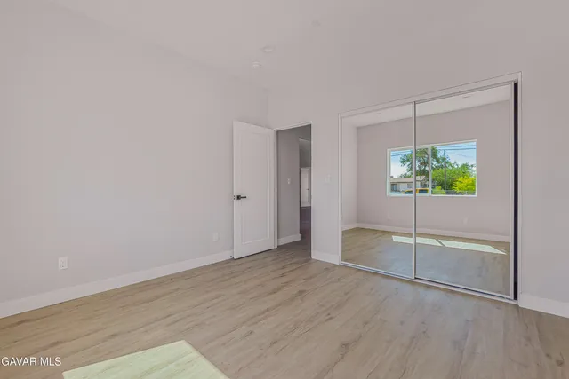 an empty room with wooden floor and window
