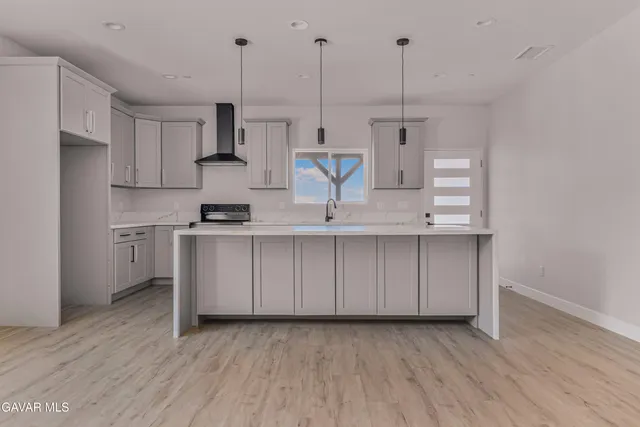 a kitchen with stainless steel appliances granite countertop a sink a stove a refrigerator and island with wooden floor