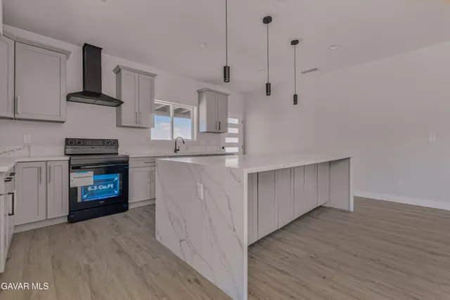 a kitchen with stainless steel appliances a stove refrigerator and a wooden floor