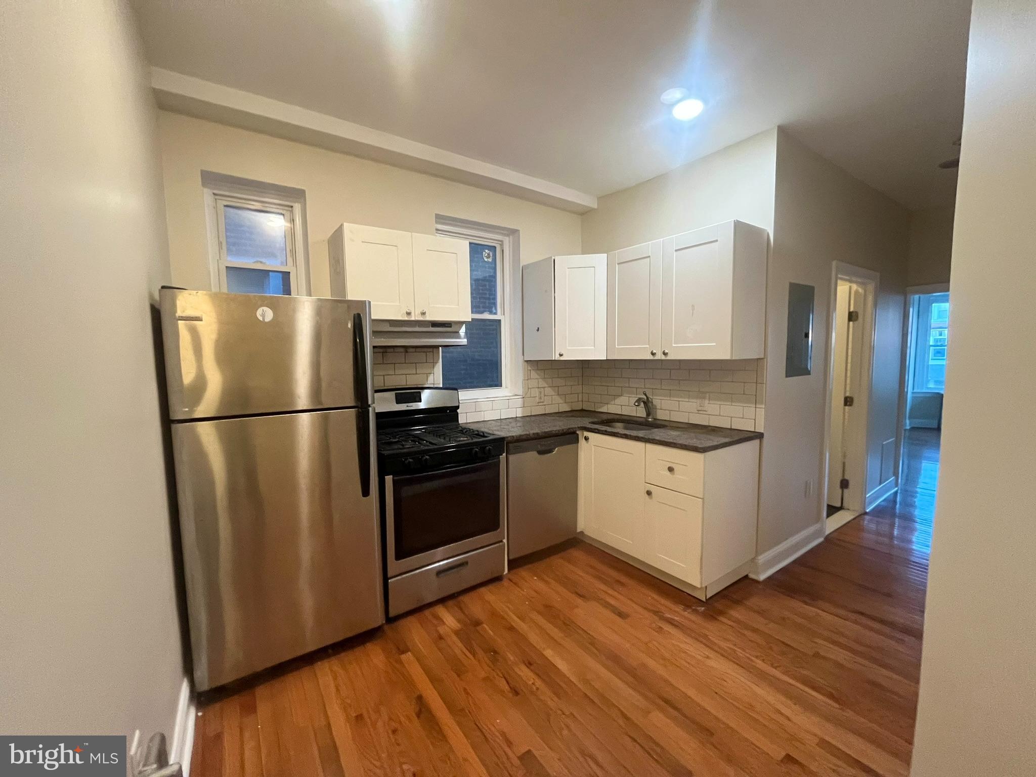 4946 Walnut Street, Unit 2F Philadelphia, PA 19139 - Photo 6 of 20 a kitchen with a refrigerator wooden floor and a window