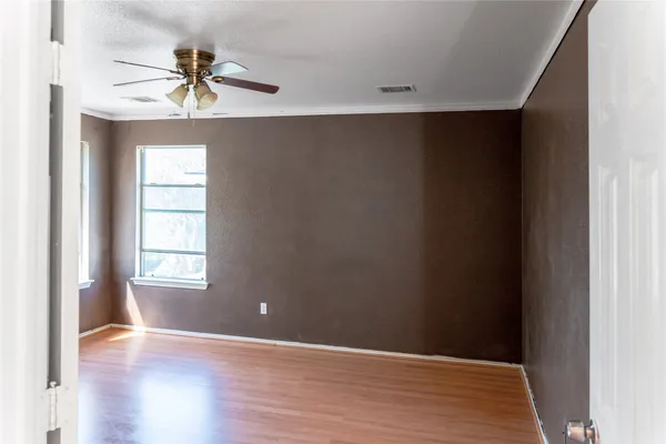 a view of empty room with wooden floor and fan