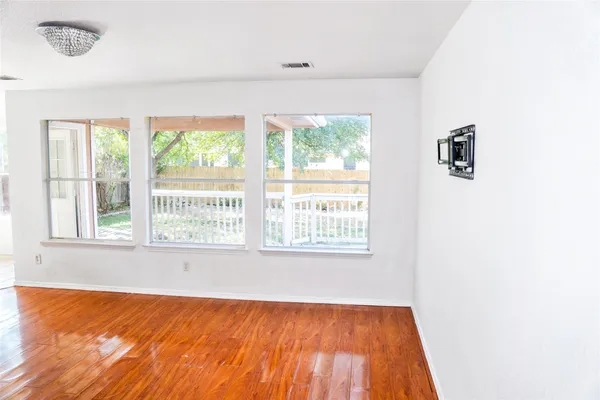 an empty room with wooden floor closet and windows