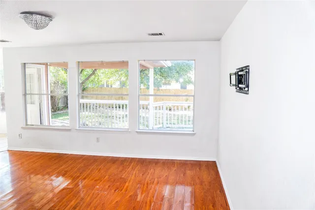 an empty room with wooden floor and windows