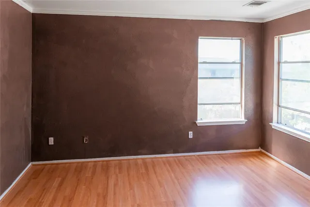 an empty room with wooden floor closet and windows