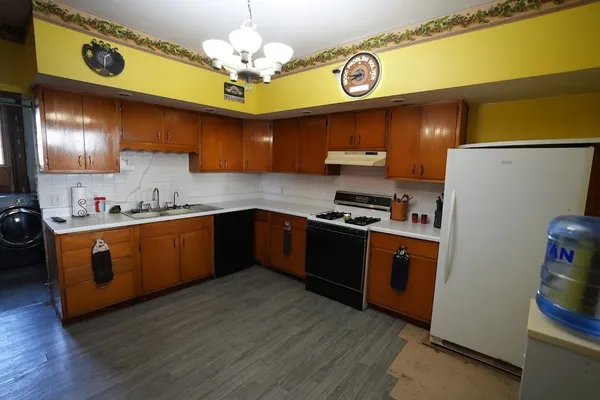 a kitchen with stainless steel appliances granite countertop a refrigerator a sink dishwasher a stove and a dining table with wooden floor