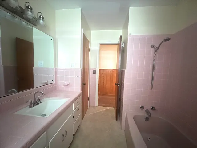 a bathroom with a tub sink double vanity granite tub shower and a mirror