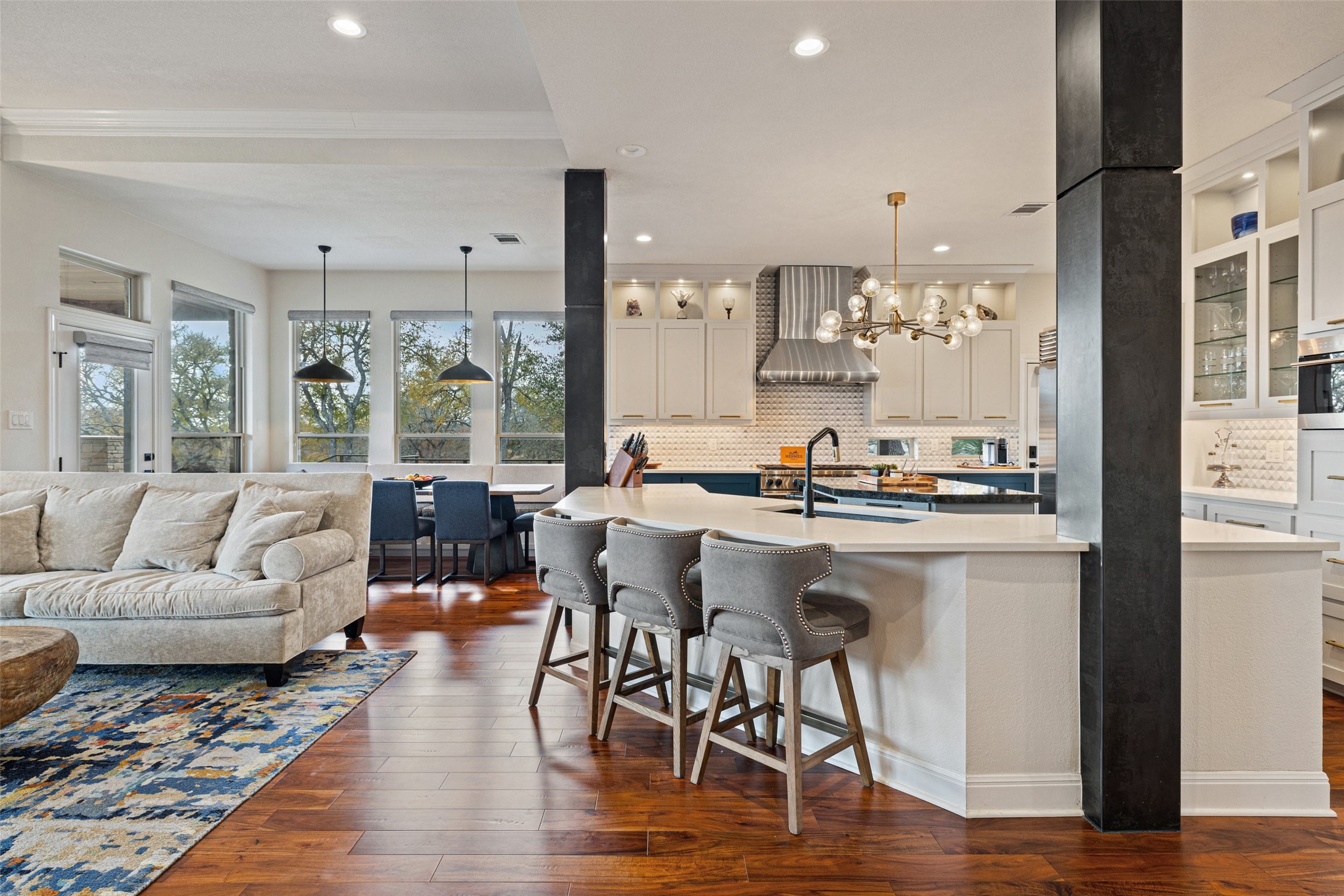 751 Prochnow Road Dripping Springs, TX 78620 - Photo 11 of 40 Kitchen featuring a kitchen bar, hanging light fixtures, white cabinets, wall chimney range hood, and backsplash