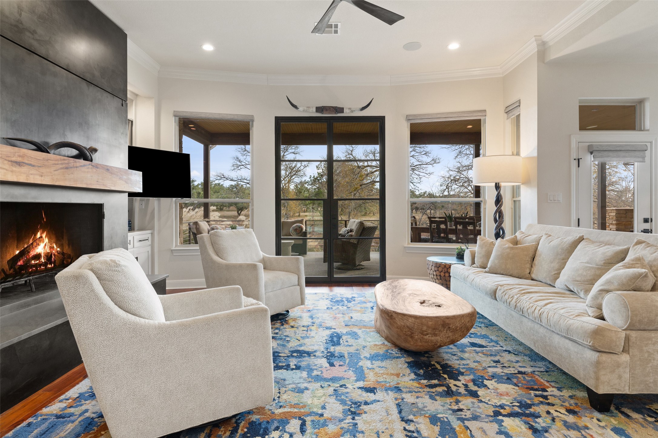 751 Prochnow Road Dripping Springs, TX 78620 - Photo 9 of 40 Living room with crown molding, a large fireplace, ceiling fan, and hardwood / wood-style floors