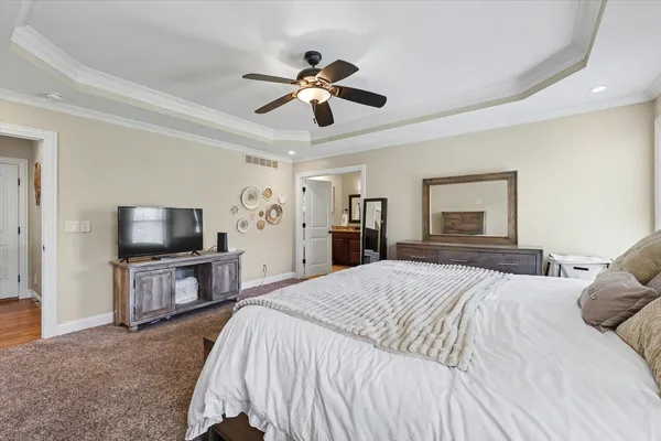 a bedroom with a large bed a flat tv screen and dresser