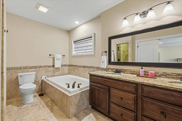 a bathroom with a granite countertop toilet sink and mirror
