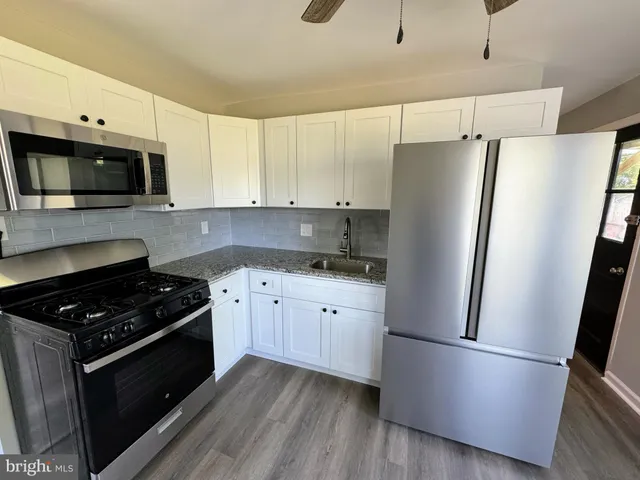 a kitchen with stainless steel appliances a refrigerator a sink and white cabinets