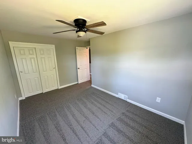 a view of an empty room with a chandelier fan