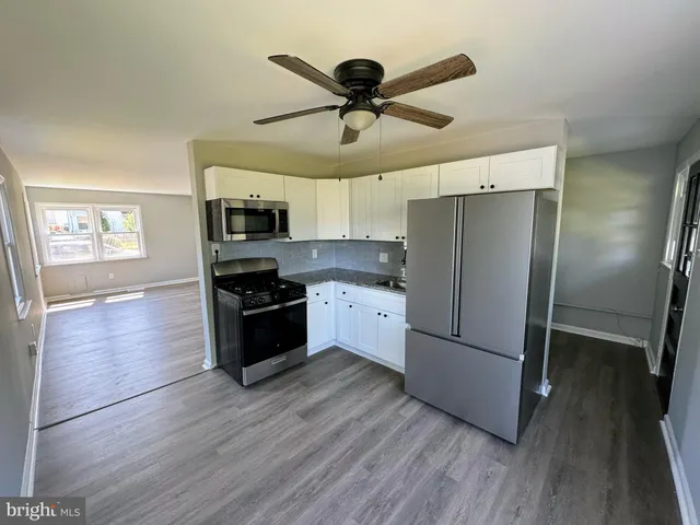 a kitchen with granite countertop a refrigerator a stove a microwave and wooden floor