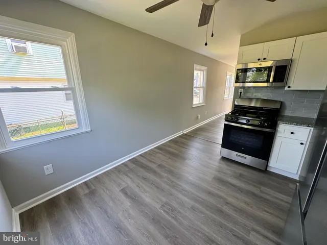 a kitchen with granite countertop wooden floors appliances and cabinets